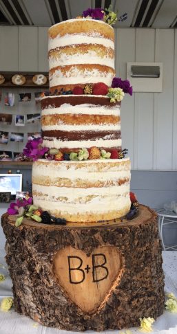 Three teared vanilla mixed berry naked wedding cake, filed with mixed berry compote, vanilla whip cream with fresh flowers, fresh berries and vanilla buttercream.